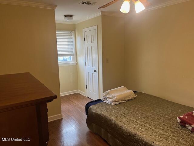 bedroom with dark hardwood / wood-style floors, ceiling fan, and ornamental molding