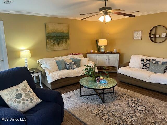 living room featuring ornamental molding, ceiling fan, and dark wood-type flooring