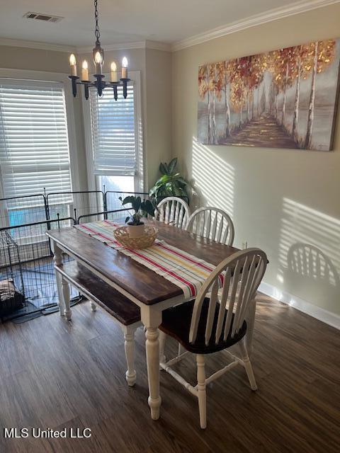 dining room with dark hardwood / wood-style floors, ornamental molding, and a notable chandelier