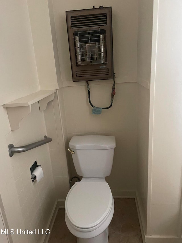 bathroom with heating unit, toilet, and tile patterned flooring