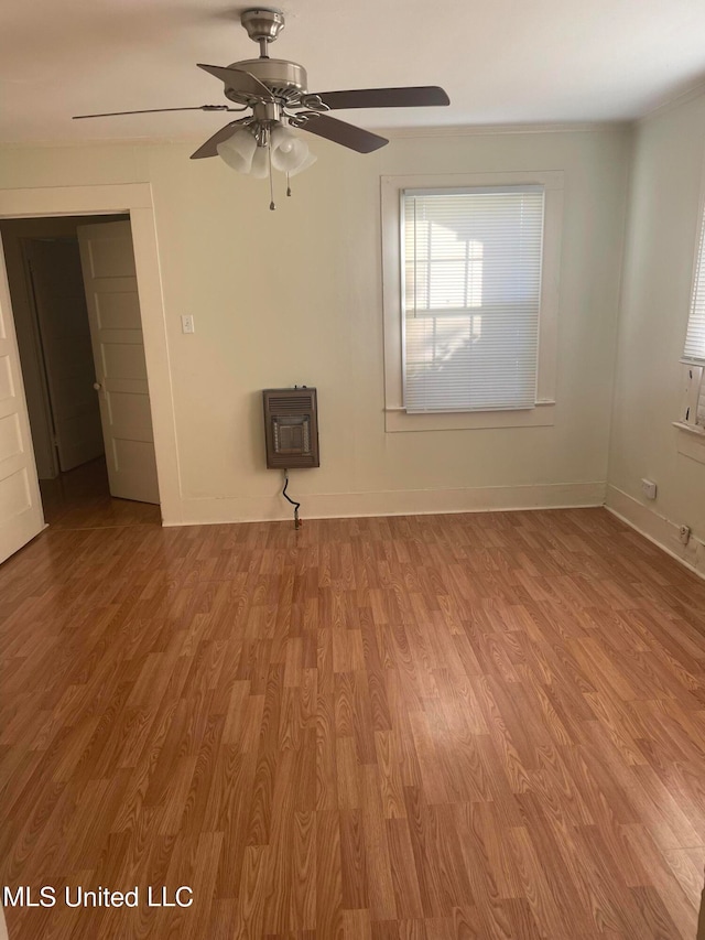 spare room featuring ceiling fan, heating unit, and light wood-type flooring