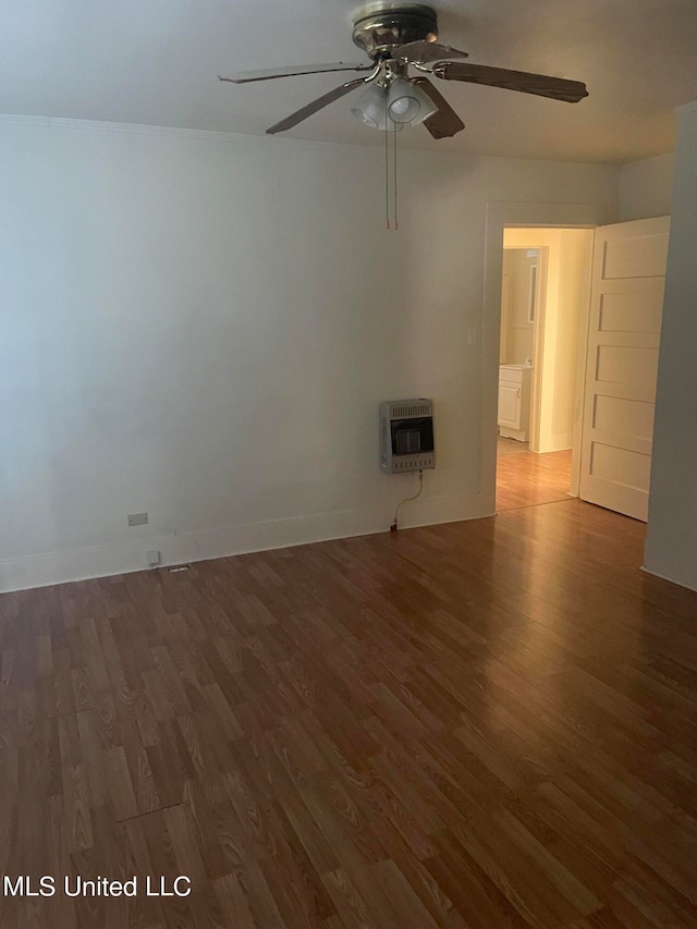 empty room featuring dark wood-type flooring, ceiling fan, and heating unit