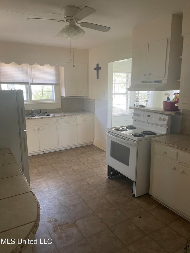 kitchen with white appliances, ceiling fan, a wealth of natural light, and white cabinets