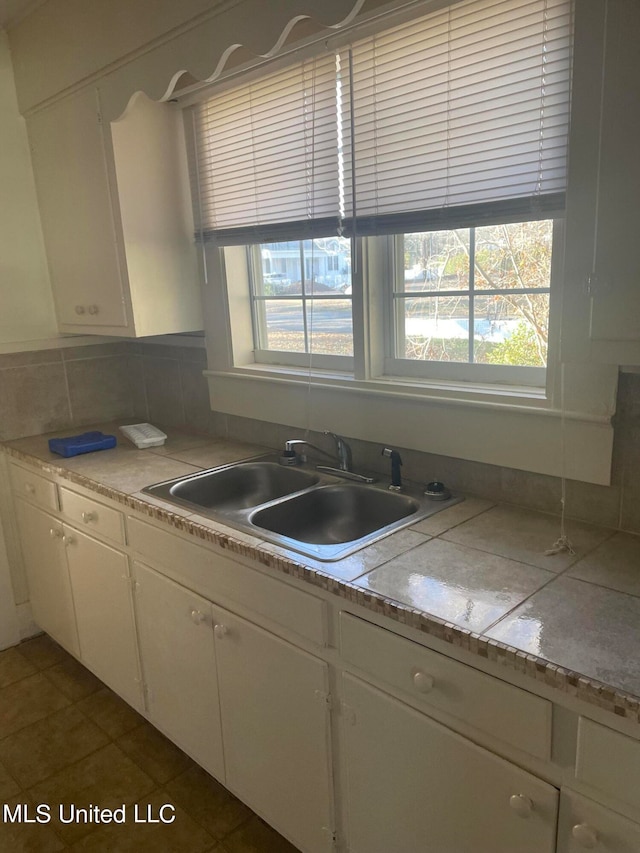 kitchen featuring white cabinetry, decorative backsplash, sink, and dark tile patterned floors