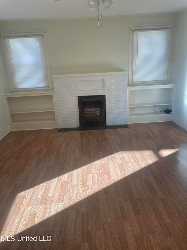 unfurnished living room featuring a brick fireplace, dark hardwood / wood-style floors, and ceiling fan