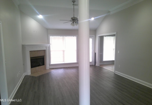 unfurnished living room with lofted ceiling, dark wood-type flooring, ceiling fan, ornamental molding, and a tiled fireplace