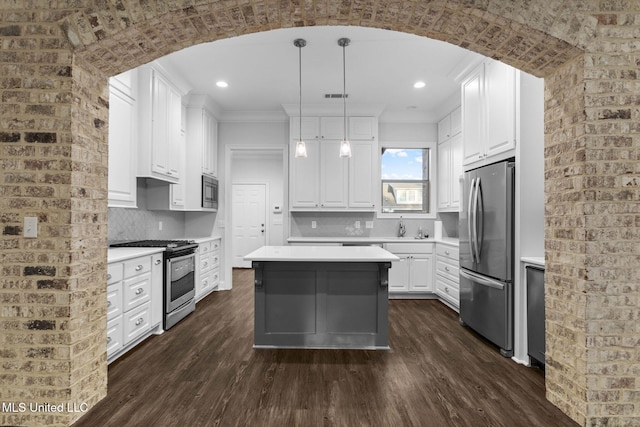 kitchen featuring arched walkways, appliances with stainless steel finishes, dark wood finished floors, and light countertops