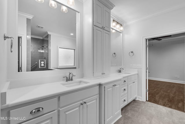 full bath with double vanity, a tile shower, crown molding, and a sink