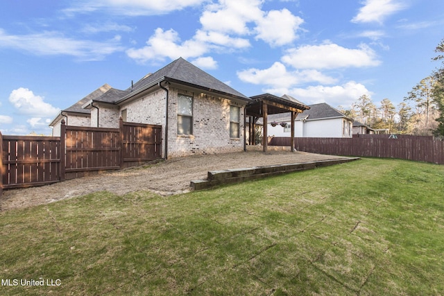 back of property featuring brick siding, a lawn, a fenced backyard, and roof with shingles