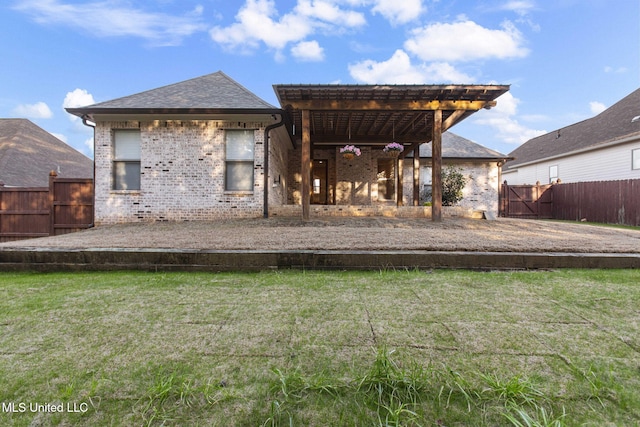 rear view of property with brick siding, a lawn, and fence