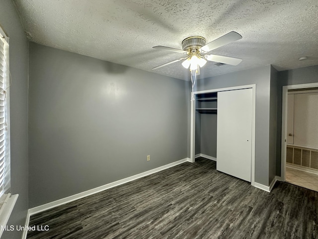 unfurnished bedroom with a closet, dark wood finished floors, a textured ceiling, and baseboards