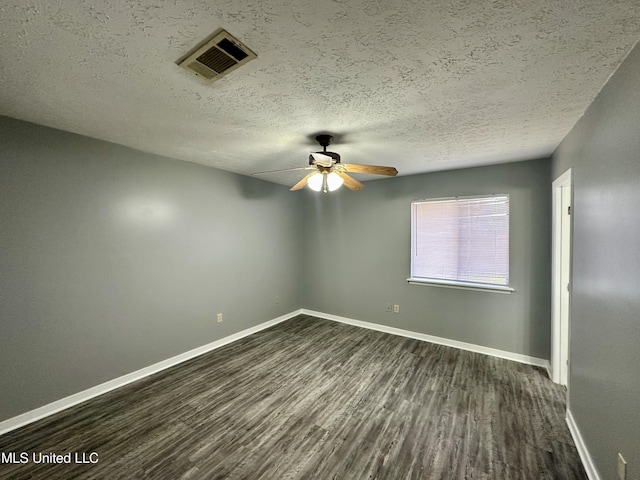 spare room with a textured ceiling, dark wood-style flooring, visible vents, and baseboards