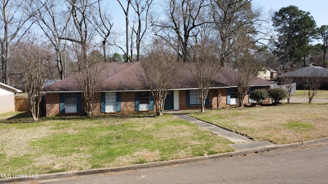 ranch-style house featuring brick siding, fence, and a front lawn