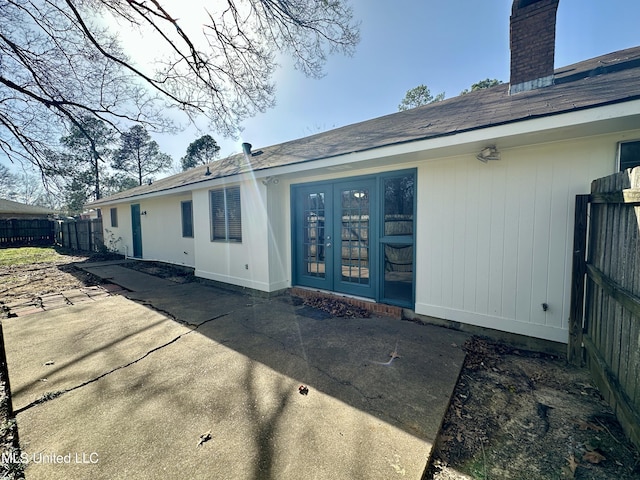 rear view of house featuring french doors, a patio area, fence, and a chimney