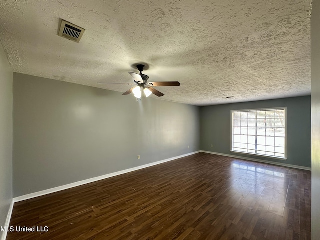 unfurnished room featuring dark wood-style flooring, visible vents, and baseboards