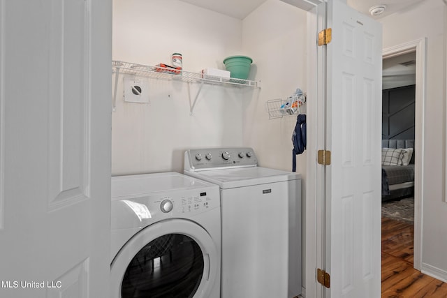 laundry area with laundry area, washing machine and dryer, and light wood-style flooring