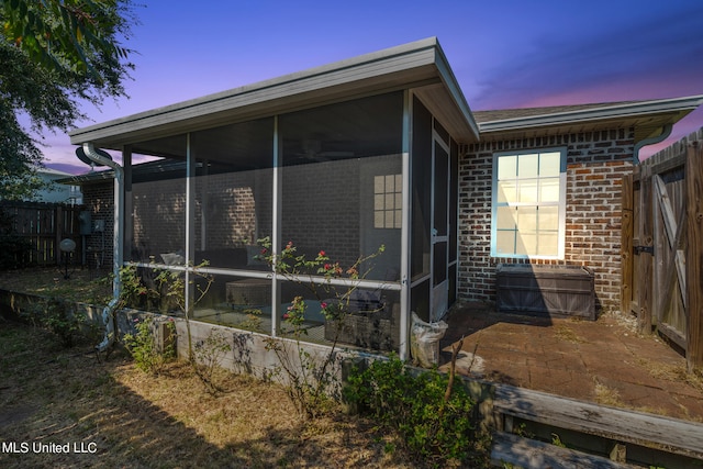 view of home's exterior featuring fence, a sunroom, a patio area, and brick siding