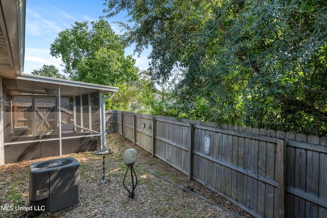 view of yard with a sunroom, central AC unit, and a fenced backyard