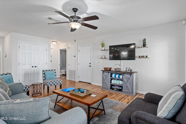 living area featuring baseboards, a ceiling fan, and wood finished floors