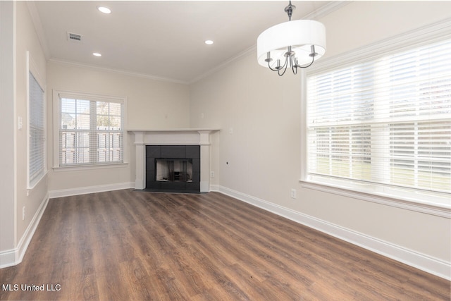 unfurnished living room featuring a tile fireplace, a chandelier, dark wood-type flooring, and crown molding