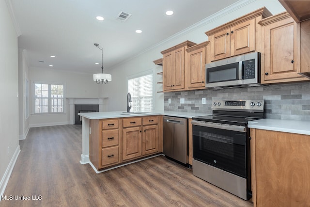 kitchen featuring backsplash, hanging light fixtures, sink, appliances with stainless steel finishes, and kitchen peninsula