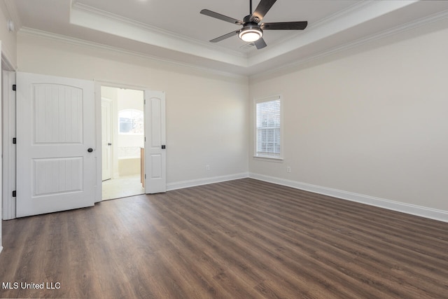 empty room featuring dark hardwood / wood-style flooring, a tray ceiling, ceiling fan, and ornamental molding