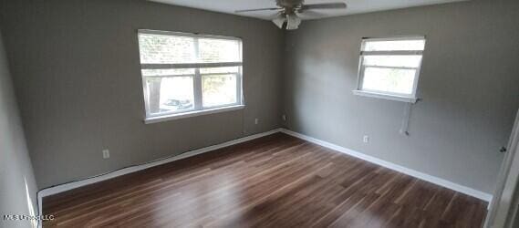 empty room featuring dark wood-type flooring and ceiling fan