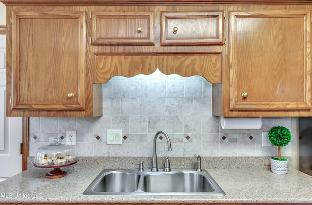 kitchen with tasteful backsplash, sink, and light stone counters