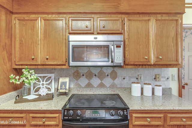 kitchen featuring light stone counters, black electric range oven, and decorative backsplash