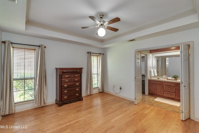 unfurnished bedroom with ensuite bath, a raised ceiling, ceiling fan, ornamental molding, and light hardwood / wood-style flooring