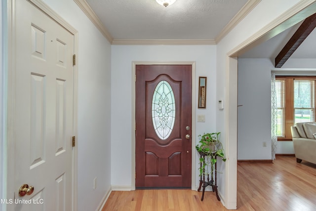 entrance foyer with beamed ceiling, ornamental molding, a textured ceiling, and light wood-type flooring