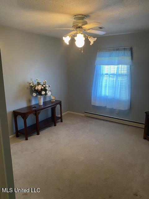 710 Eubanks Rd, Alligator, MS 38720 - spare room featuring baseboard heating, a ceiling fan, light colored carpet, baseboards, and a textured ceiling