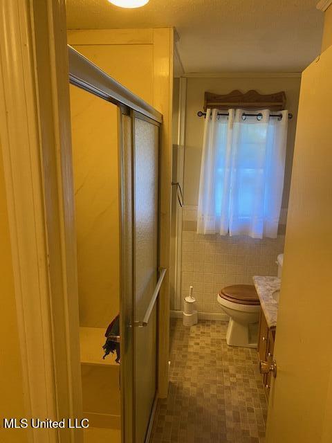 710 Eubanks Rd, Alligator, MS 38720 - bathroom featuring vanity, a shower stall, toilet, and tile walls