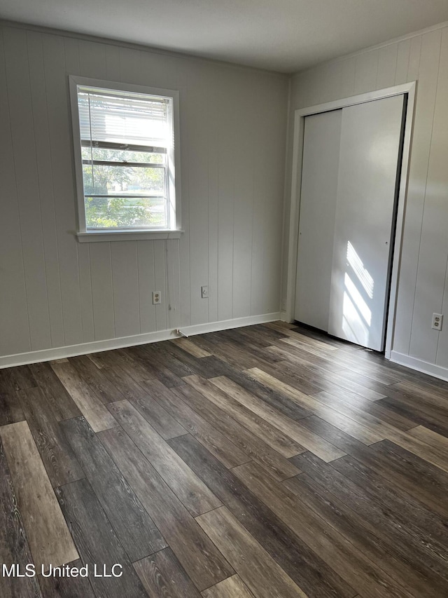 unfurnished bedroom with dark wood-type flooring and a closet