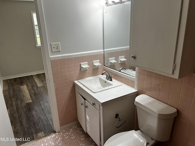 bathroom featuring toilet, vanity, tile walls, and hardwood / wood-style flooring