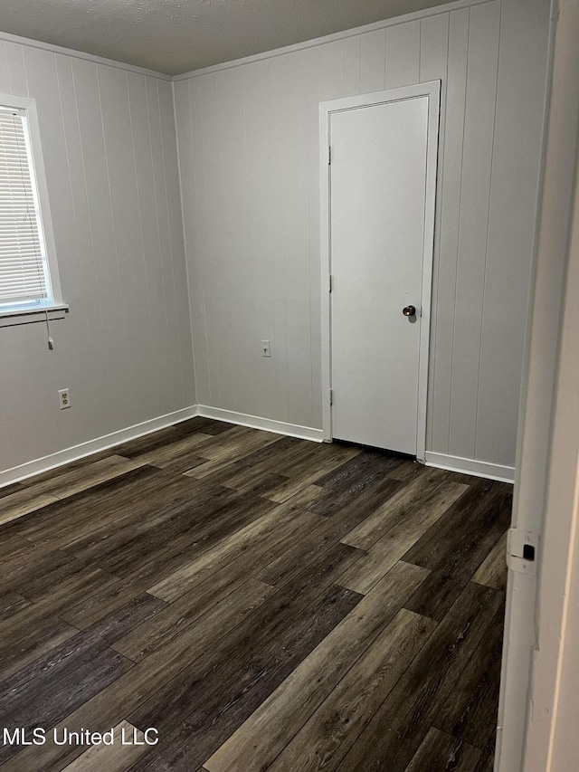 unfurnished room with dark wood-type flooring and a textured ceiling