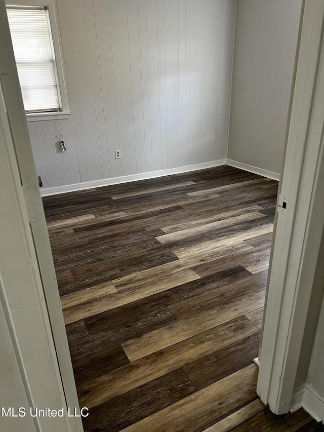 spare room with dark wood-type flooring and wooden walls