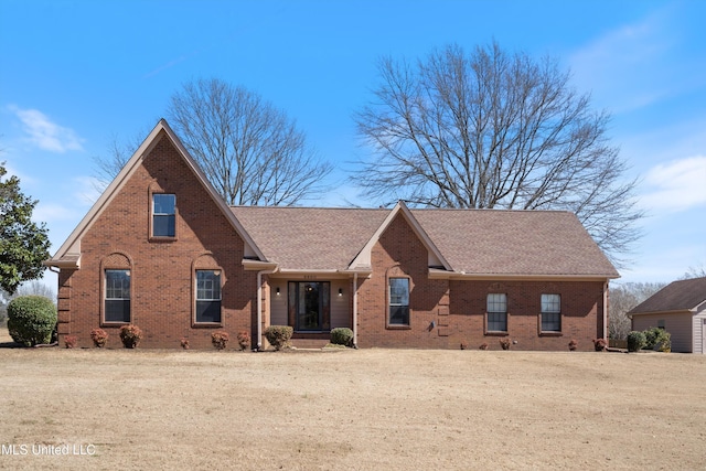 view of front of house with brick siding and roof with shingles