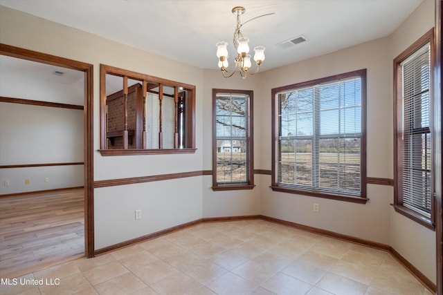 unfurnished room featuring visible vents, baseboards, and a chandelier