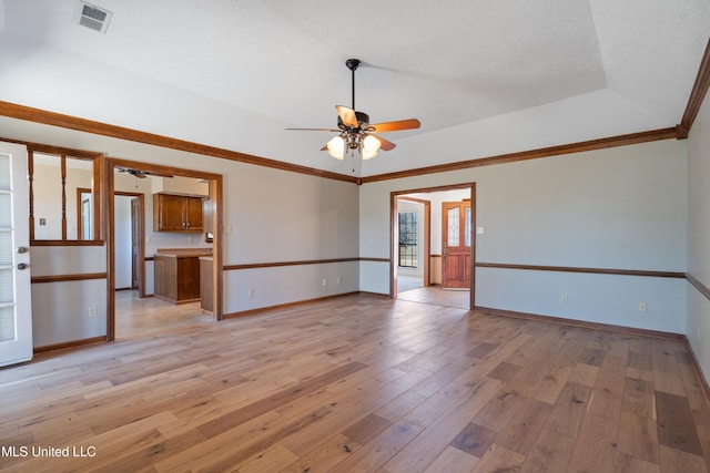 empty room with light wood-style flooring, baseboards, a raised ceiling, and ceiling fan