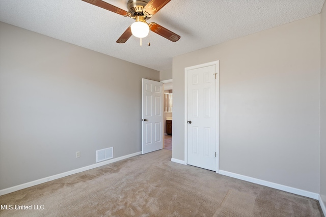 interior space featuring baseboards, visible vents, ceiling fan, a textured ceiling, and carpet flooring