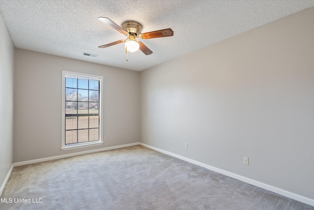 carpeted spare room featuring visible vents, a ceiling fan, baseboards, and a textured ceiling