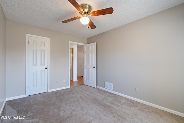 unfurnished bedroom with visible vents, a ceiling fan, a textured ceiling, carpet flooring, and baseboards