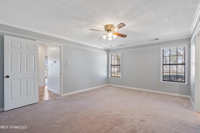 spare room featuring visible vents, ornamental molding, a textured ceiling, light colored carpet, and ceiling fan