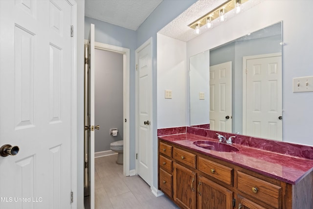 bathroom with vanity, baseboards, tile patterned flooring, a textured ceiling, and toilet