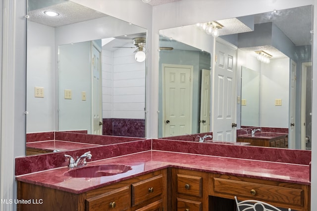 bathroom with a sink, a textured ceiling, ceiling fan, and double vanity