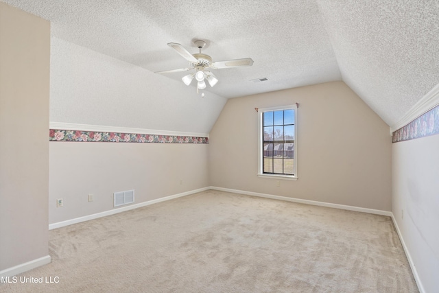 additional living space with vaulted ceiling, carpet flooring, a ceiling fan, and visible vents