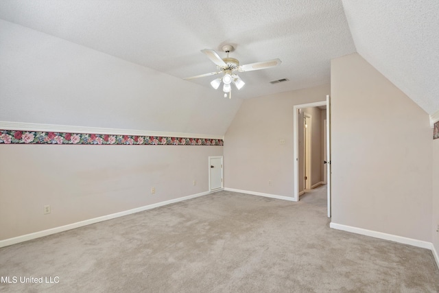 bonus room featuring baseboards, visible vents, ceiling fan, a textured ceiling, and light carpet