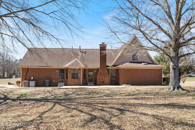 back of property featuring cooling unit, brick siding, a chimney, and a patio area