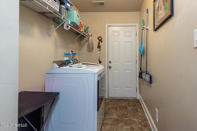 clothes washing area with washing machine and dryer, stone finish flooring, laundry area, baseboards, and visible vents